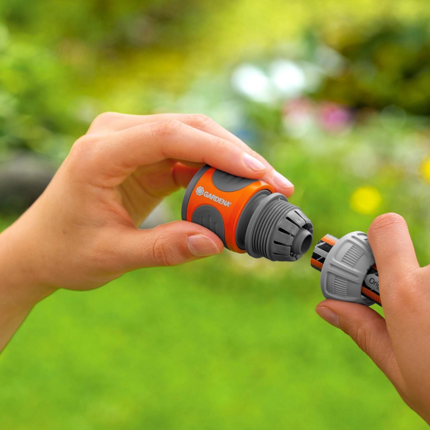 Gardena Schlauchverbinder-Satz (13-15mm) beim Zusammenstecken in Händen vor grünem Hintergrund.