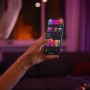 Frau steuert Philips Hue Perifo Leuchte per App auf Smartphone. Schwarze Pendelleuchte.