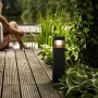 Schwarze Philips myGarden LED Sockelleuchte Parterre auf Holzdeck mit Garten im Hintergrund.
