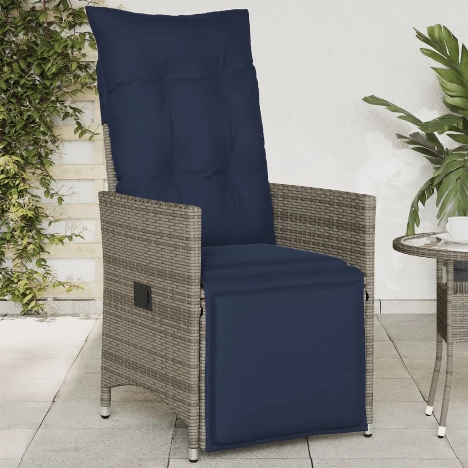 Grauer Poly Rattan Gartensessel, verstellbar, mit marineblauen Kissen auf Terrasse.
