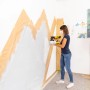Frau sprüht Wand mit Wagner Akku-Farbsprühsystem W 600 FLEXiO. Sprühgerät für Innenfarben.