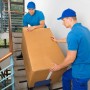 Zwei Monteure tragen eine verpackte Respekta Küchenzeile die Treppe hoch. OBI Liefer- und Aufbauservice.