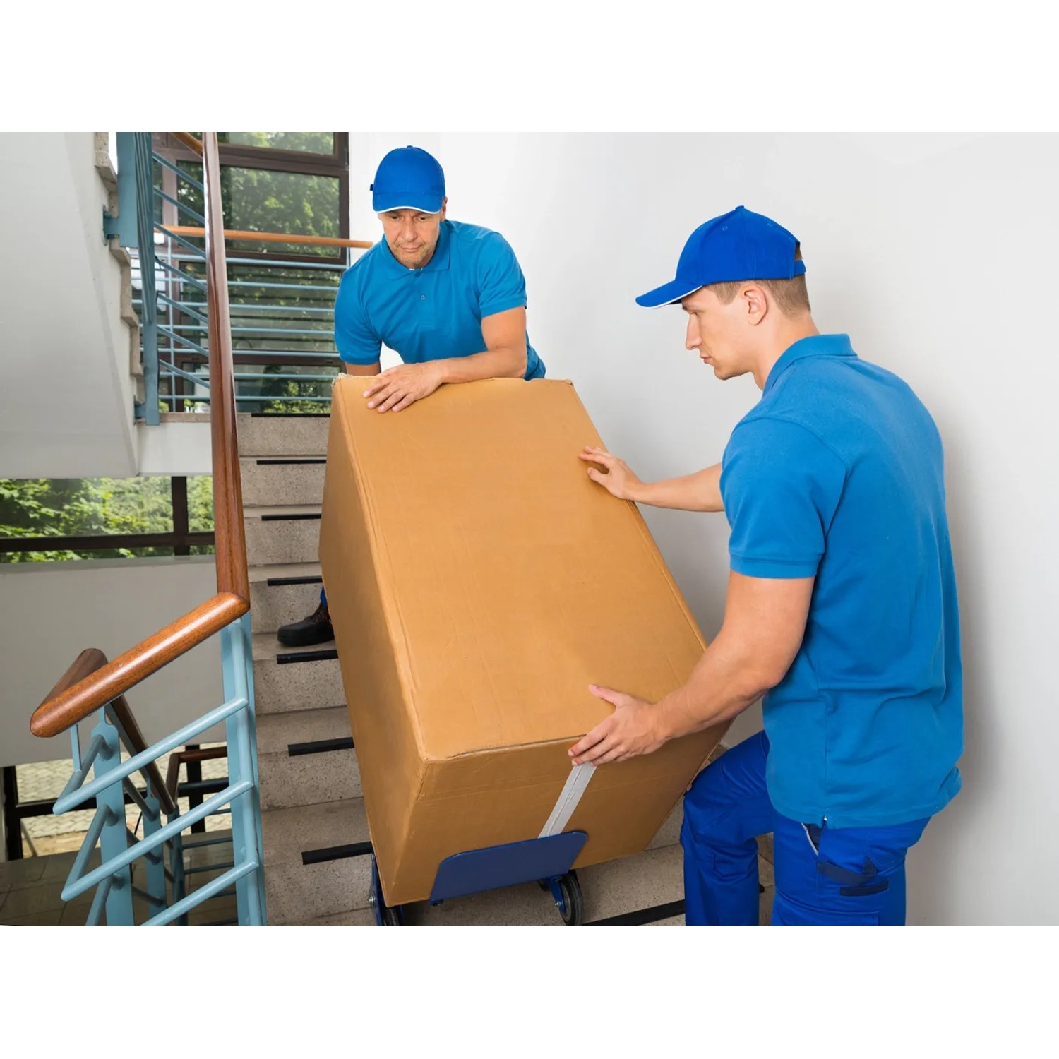 Zwei Monteure tragen eine verpackte Respekta Küchenzeile die Treppe hoch. OBI Liefer- und Aufbauservice.