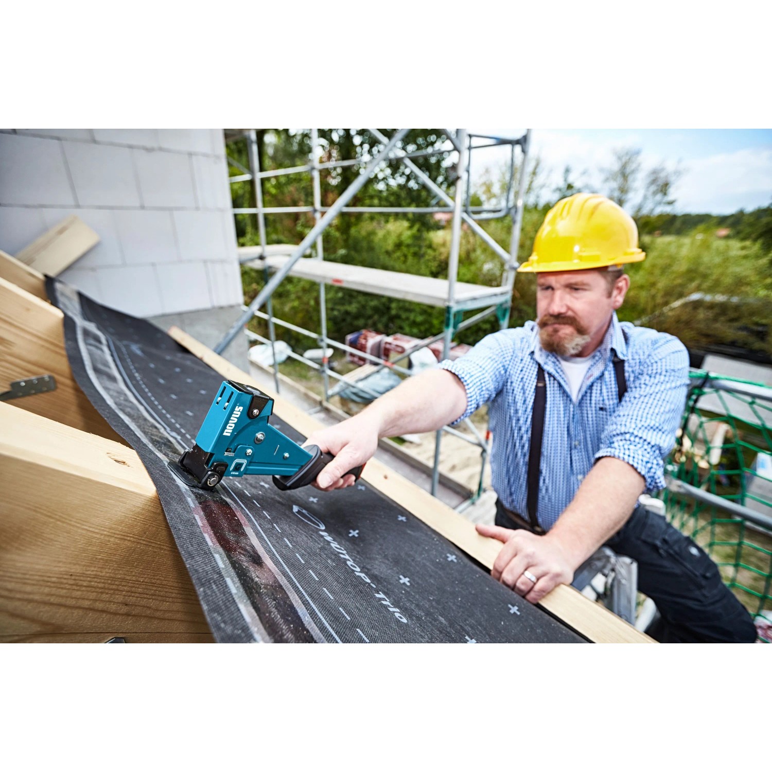 Novus Hammertacker J-055 im Einsatz: Handwerker befestigt Bitumenschindeln auf einem Dach.