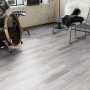 Heller Laminatboden im Pinie Sea Pine Dekor, verlegt in einem Raum mit Schlagzeug und Stühlen.