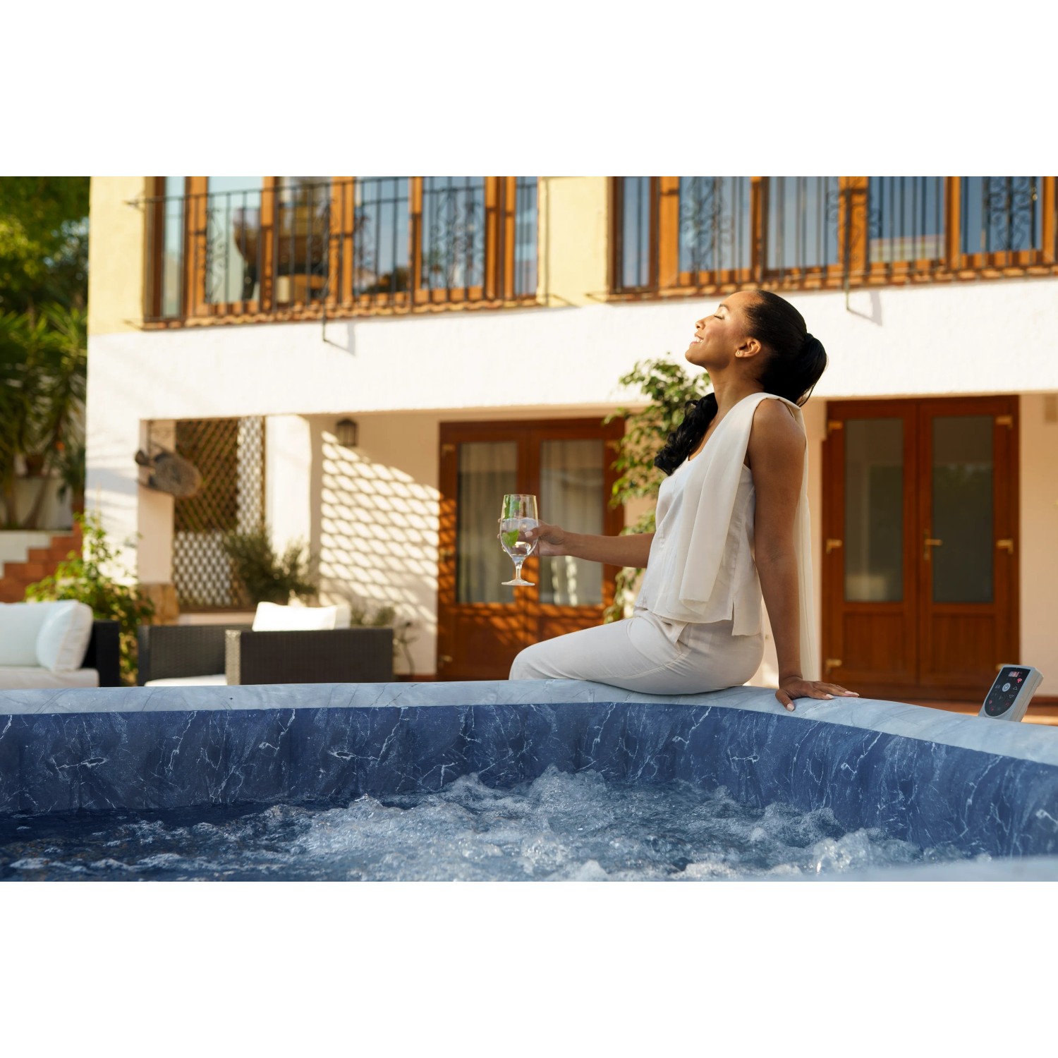 Bestway Whirlpool San Francisco für 7 Personen in Marmor-Optik mit Frau und Getränk im Garten.