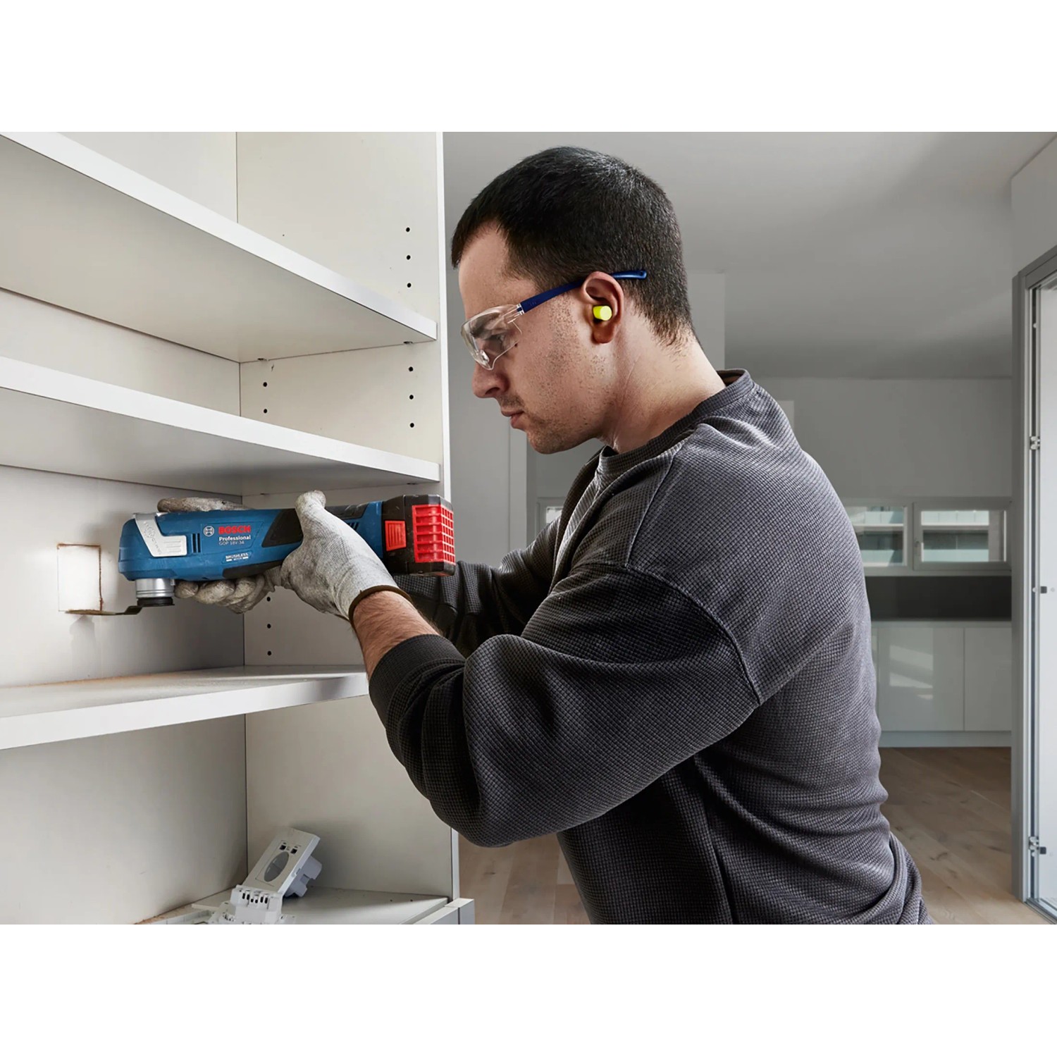 Bosch Professional GOP 18V-34 Akku-Multifunktionswerkzeug im Einsatz beim Sägen in einem weißen Regal.