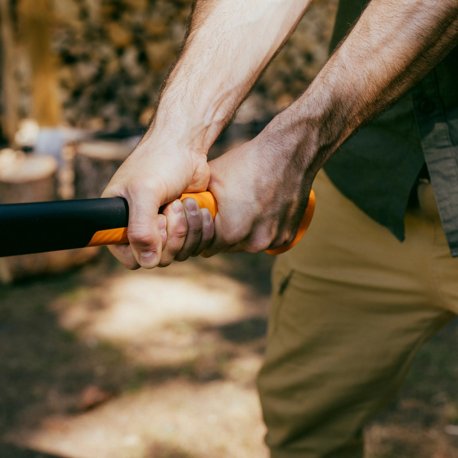 Nahaufnahme: Hände halten Fiskars Spaltaxt X32 mit orange-schwarzem Griff. Axt zum Holz spalten.