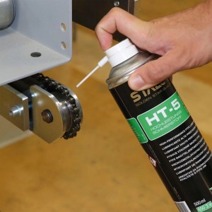 Hand sprüht Staloc HT-5 Hochleistungs-Schmierstoff auf eine Metallkette. Spezial-Spray für Lager, Gelenke & Ketten.