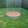 Summer Fun Gartendusche Shower UP mit runder Teak-Platte und Wasserfontäne im Garten.