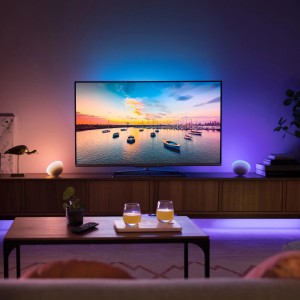 Philips Hue Go LED Tischleuchte im Wohnzimmer mit farbiger Akzentbeleuchtung.