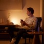 Mann nutzt Philips Hue Bloom Tischleuchte zur Akzentbeleuchtung im Wohnzimmer.
