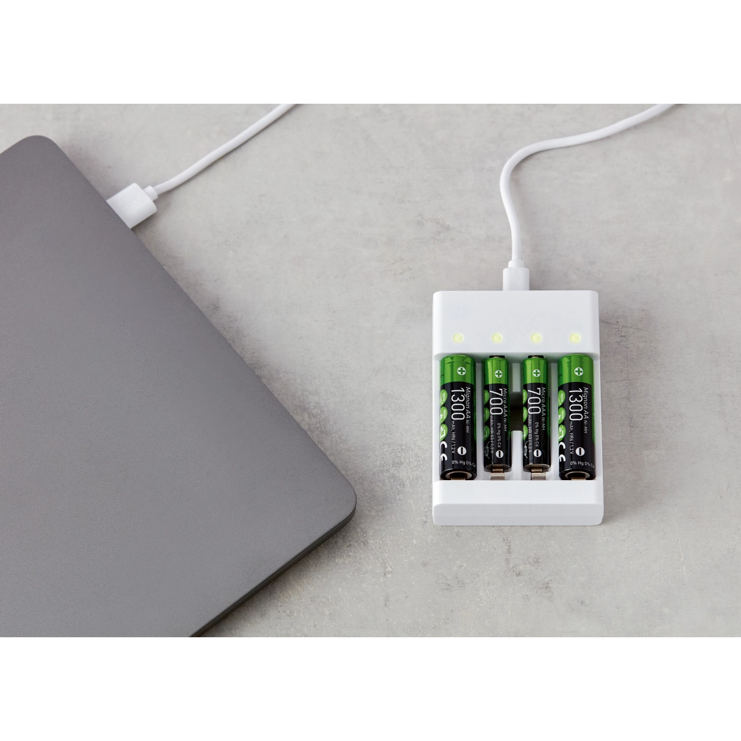 Batterie Ladegerät-Set mit AA & AAA Akkus im Ladegerät, verbunden mit Laptop.