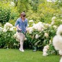 Frau trimmt Rasen mit Bosch Akku-Rasentrimmer EasyGrassCut 18V-230 im Garten.