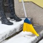 Sonneck Universalbesen mit Stiel beim Schneekehren auf einer Treppe. Gelbe Borsten, Stahlstiel.