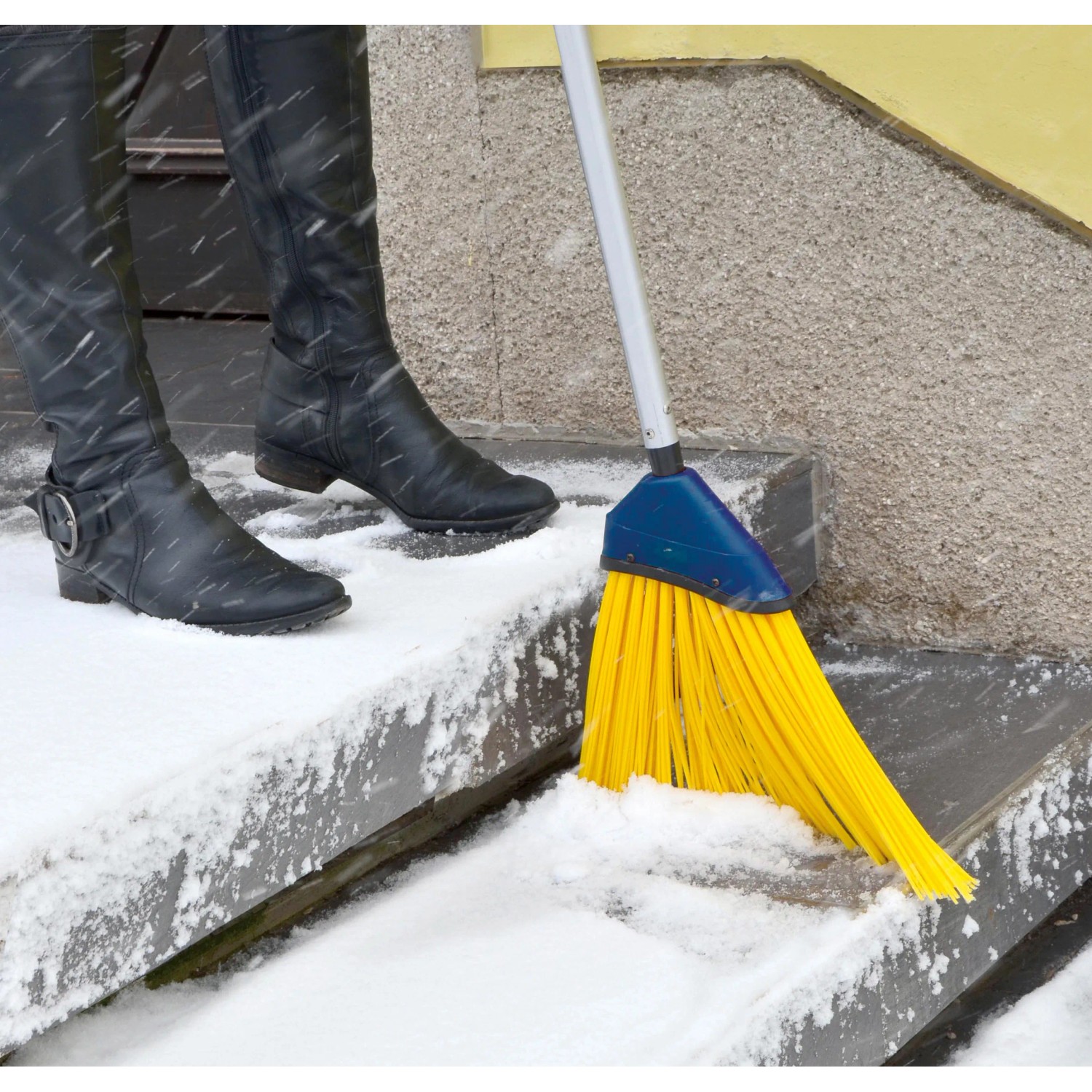 Sonneck Universalbesen mit Stiel beim Schneekehren auf einer Treppe. Gelbe Borsten, Stahlstiel.