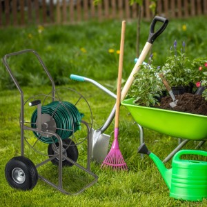Brauner Relaxdays Stahl Gartenschlauchwagen mit Kurbel, grüner Schlauchtrommel und Rädern im Garten.