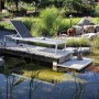 Anthrazitfarbene Acamp Sonnenliege Rimini mit Rollen auf Holzsteg am Gartenteich.