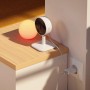 Yale Smart-Camera Innen, WLAN, Full HD, weiße Überwachungskamera auf Tisch mit Lampe.