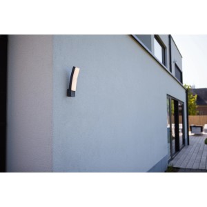 Anthrazitfarbene Lutec LED-Außenwandleuchte Kira mit gebogenem Diffusor an einer Hauswand.