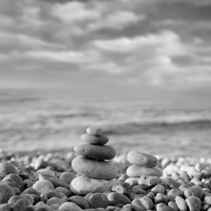 Fliesenbild Zen Stones, 16-teilig, mit gestapelten Steinen am Strand in Schwarz-Weiß.