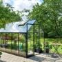 Schwarzes Halls Gewächshaus Qube 610 mit geöffnetem Dachfenster im Garten.