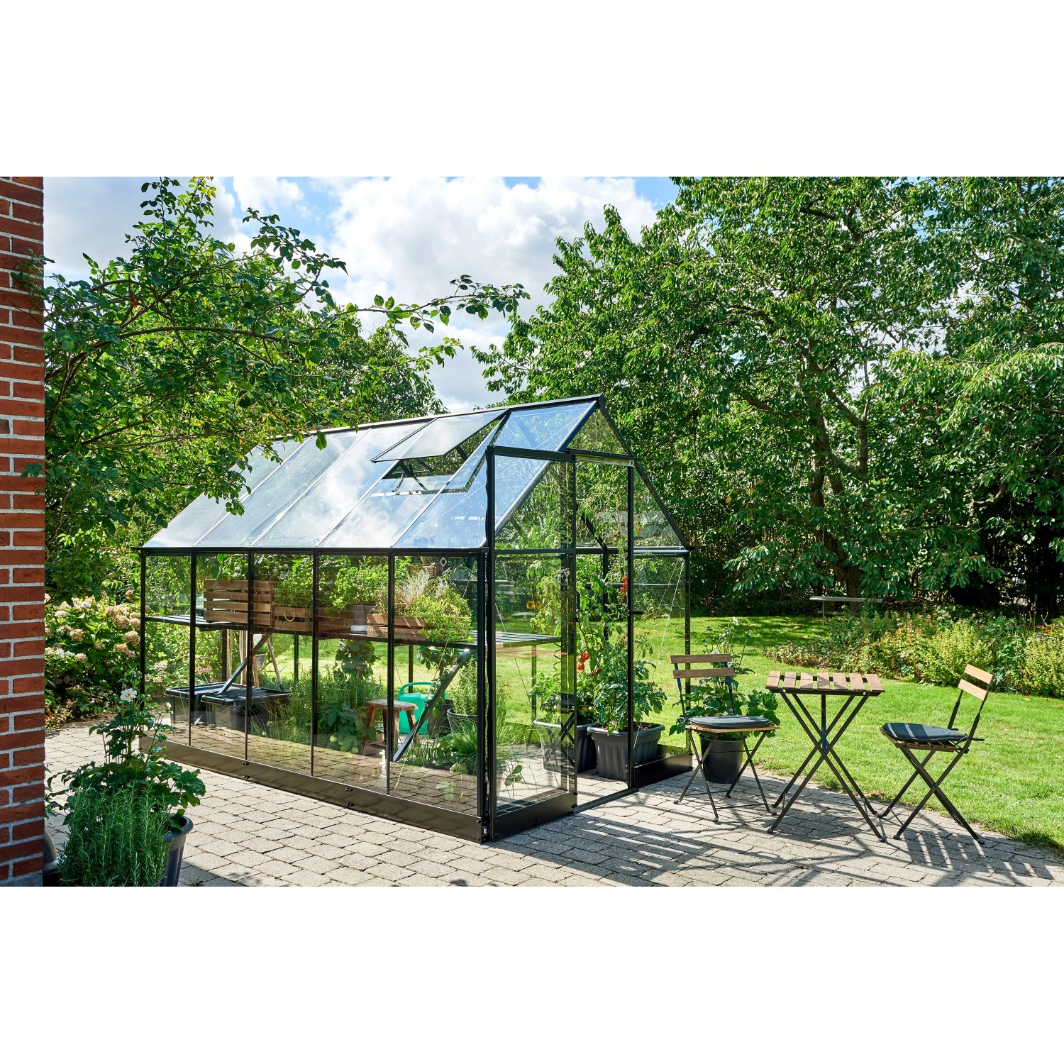 Schwarzes Halls Gewächshaus Qube 610 mit geöffnetem Dachfenster im Garten.