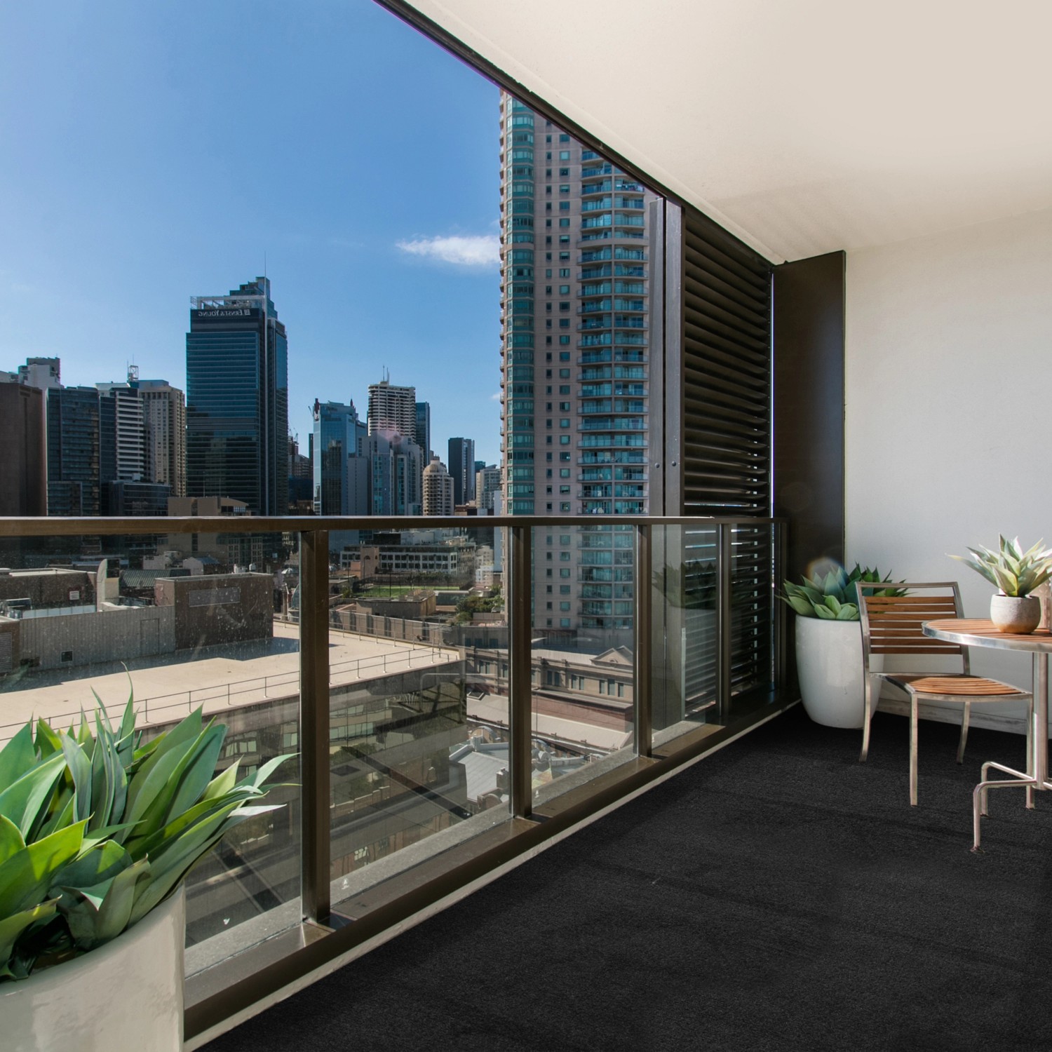 Anthrazitfarbener Primaflor Rasenteppich Comfort auf einem Balkon mit Stadtblick.