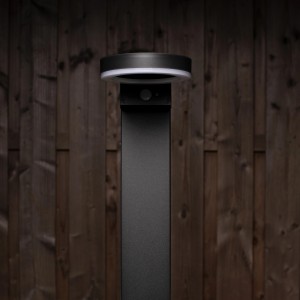 Schwarze Solar-Wegeleuchte Amsterdam mit Sensor, 6W, 600lm, 2700K, IP44 vor Holzwand.