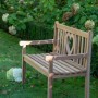 Gartenbank Herz aus Teakholz mit Herzmotiv im Garten.