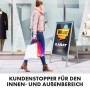 KARAT Kundenstopper aus Aluminium A1 vor Schaufenster mit Frau und Einkaufstüten.