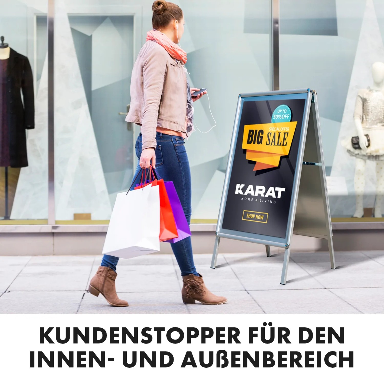 KARAT Kundenstopper aus Aluminium A1 vor Schaufenster mit Frau und Einkaufstüten.