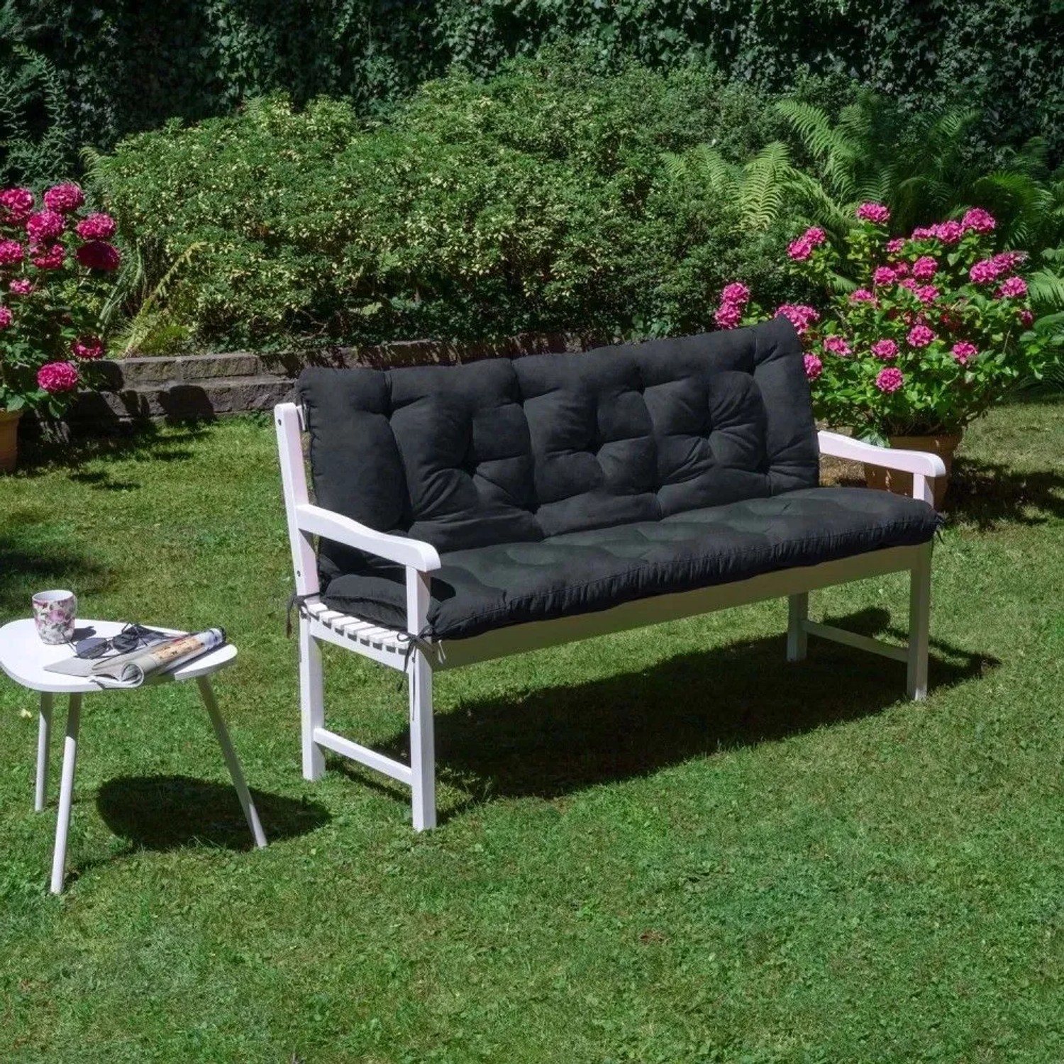 Graphitgraue Beautissu Flair BR Bankauflage 150x50cm auf weißer Gartenbank im Grünen. Gemütliches Sitzkissen für Garten & Terrasse.