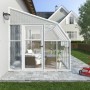 Weißes Palram Canopia Gewächshaus Sun Room (260x257cm) am Haus mit Möbeln und rotem Dreirad.