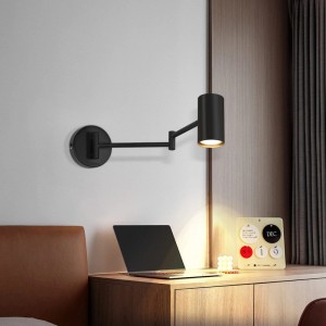 Schwarze schwenkbare Wandleuchte aus Metall, beleuchtet einen Schreibtisch. Flexibel einstellbare Lampe für Wohn- & Arbeitsbereiche.