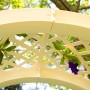 Detailansicht des weißen KHW Rosenbogens mit Rankgitter und blühenden Pflanzen.