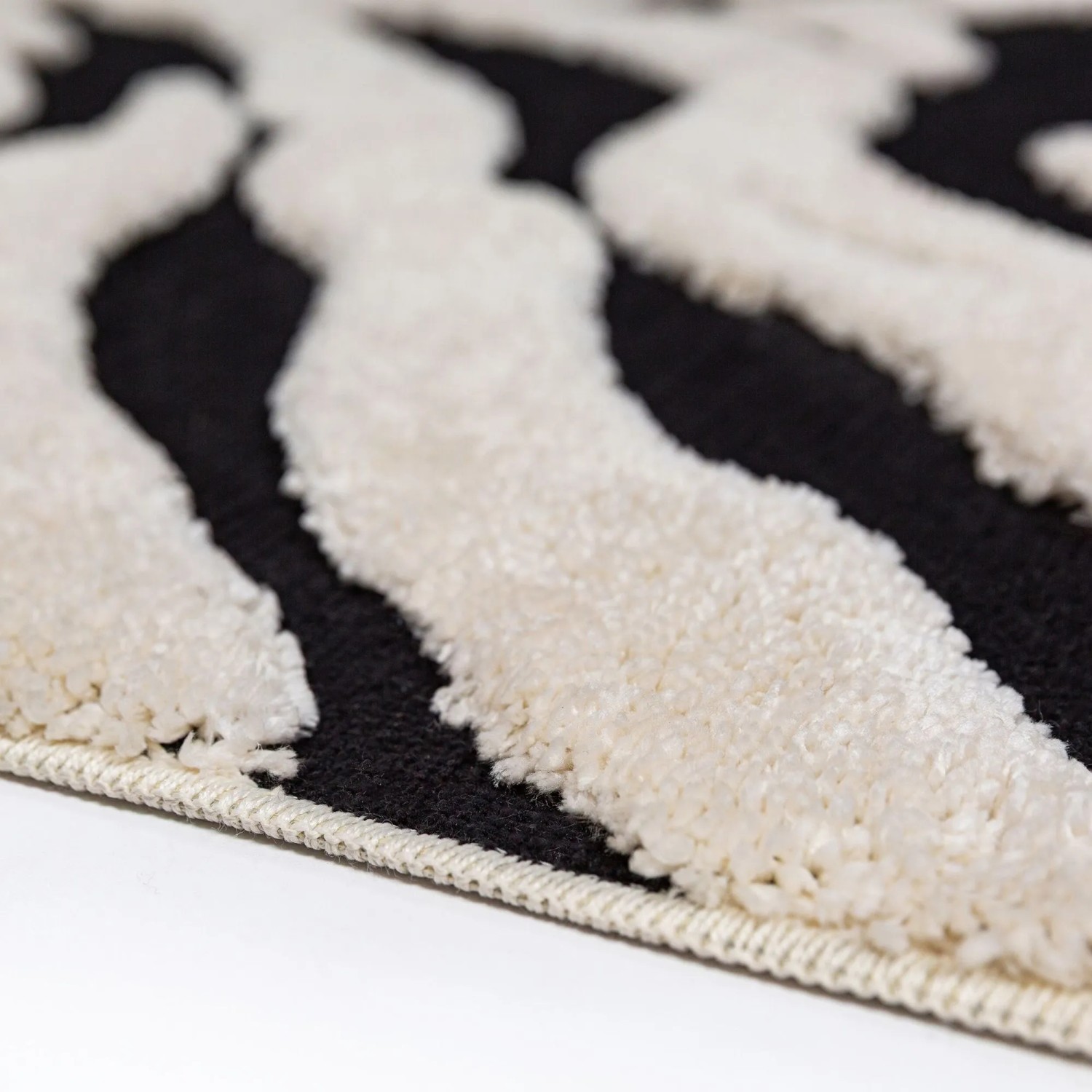 Nahaufnahme des Flair Rugs Hochflorteppichs Esra Zebra. Schwarz-weißer, zotteliger Flor mit strukturierter Hoch-Tief-Optik.