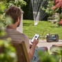 Gardena Haus- und Gartenautomat 5000 Silent Comfort mit App-Steuerung und Gartenbewässerung im Hintergrund.