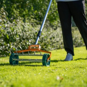 Monstershop Rasenrakel und Rollrasenlüfter (50cm) in Orange im Einsatz auf Rasen.