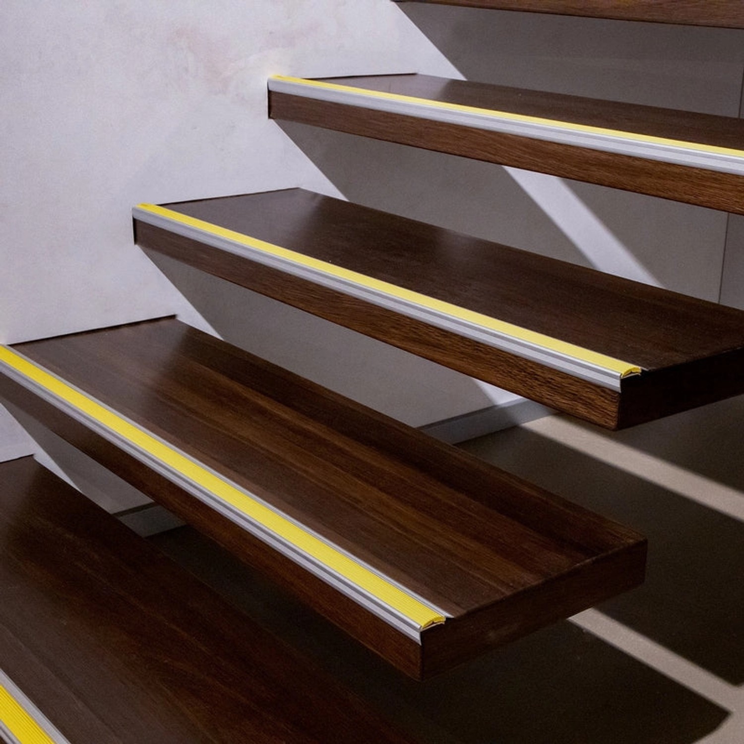 Treppe mit schwarzen KARAT Treppenkantenprofilen Power Grip mit gelber Gummieinlage.