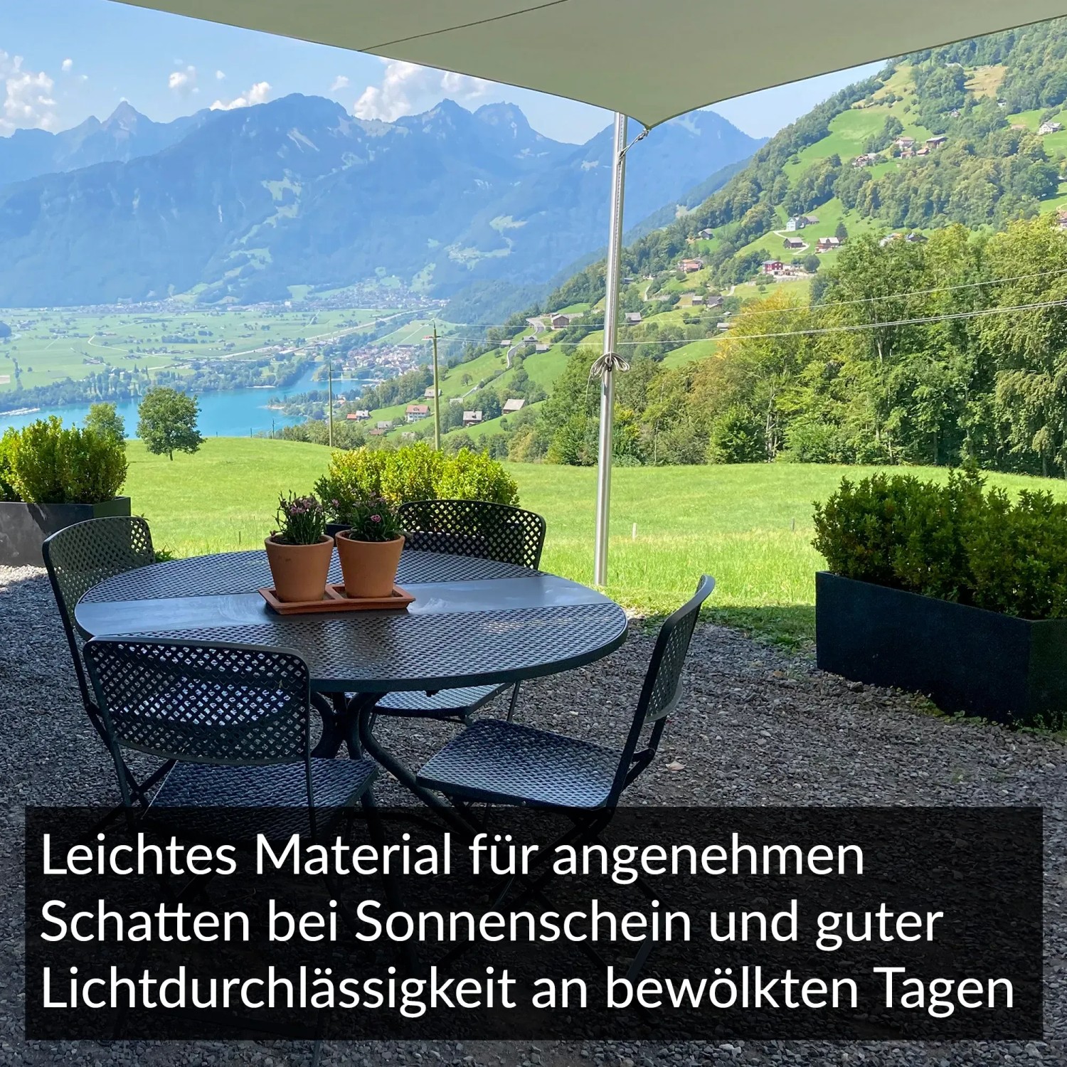 Hellgraues Toldoro Sonnensegel Dreieck über einer Gartensitzgruppe mit Bergblick.