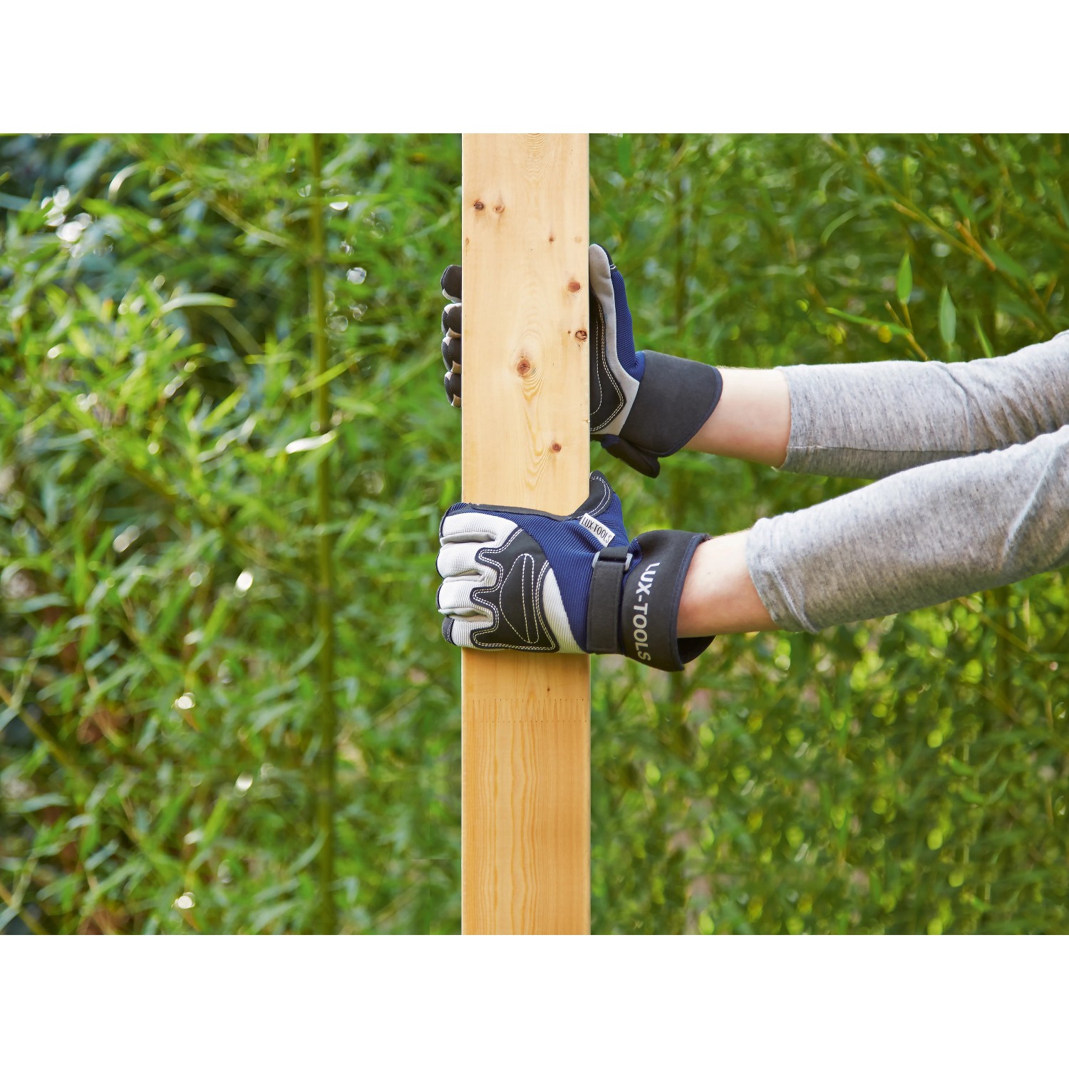 Hände mit LUX-TOOLS Arbeitshandschuhen Soft Protect Plus Gr. 8 halten Holzpfosten im Garten.
