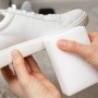 Anwendung eines Schmutzradierers auf einem weißen Lederschuh. Reinigung mit dem Schmutzradierer.