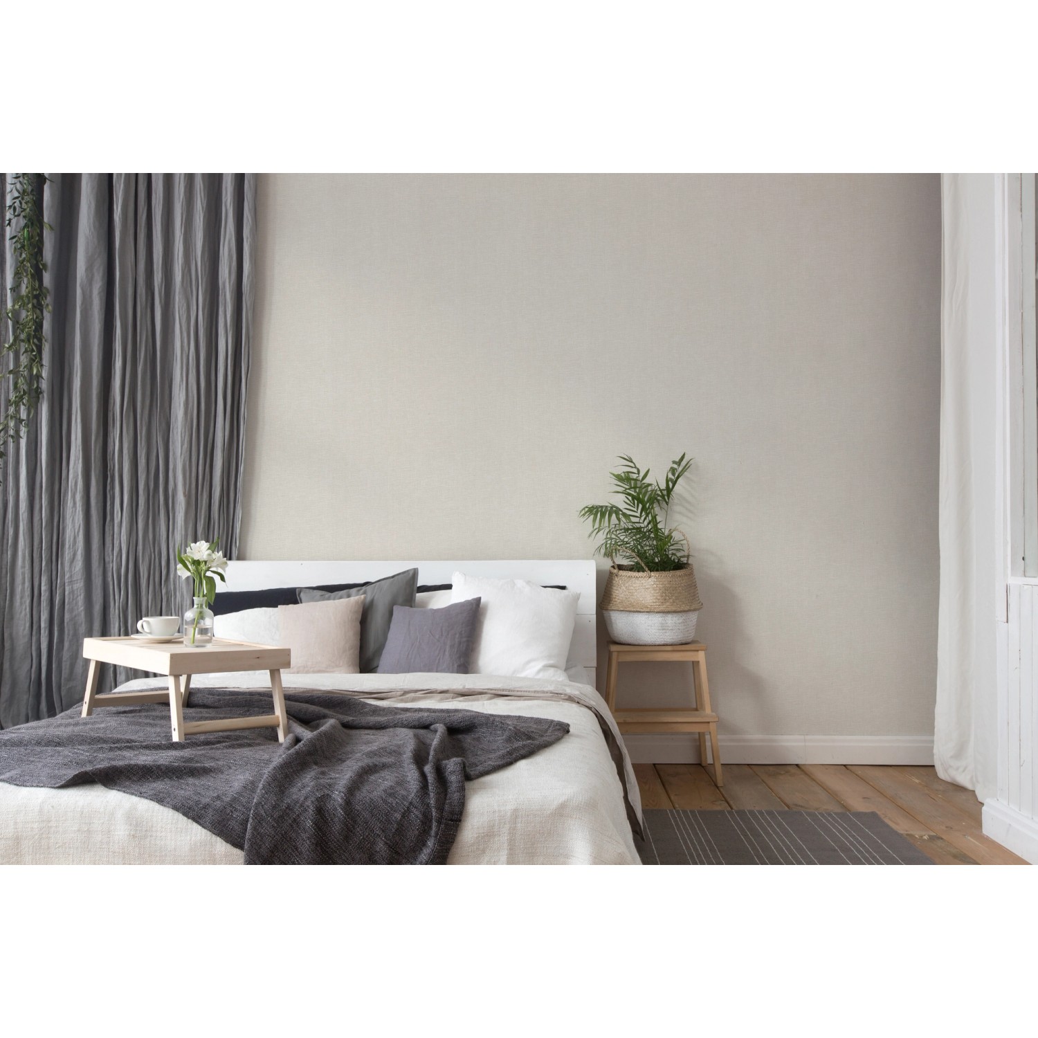 Schlafzimmer mit grauer, strukturierter Vliestapete Uni Matt FSC® an der Wand.