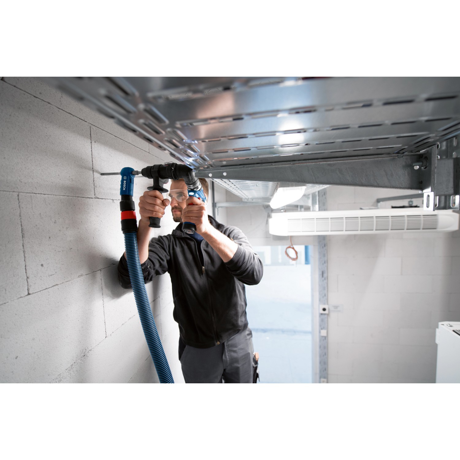 Handwerker bohrt mit Bosch Professional Bohrhammeraufsatz GFA 12-H FlexiClick in Wand.