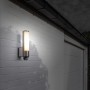 Lutec LED-Außenwandleuchte Leda mit Bewegungsmelder an weißer Hauswand.