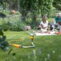 Hozelock Flexi Spray 4in1 Gartenbrause als Rasensprenger im Garten mit Familie im Hintergrund.