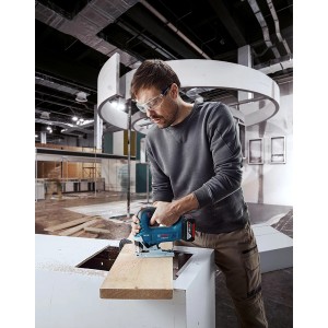 Mann sägt Holz mit Bosch Professional Akku-Stichsäge GST 18 V-125 B. Stichsäge in Blau.