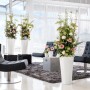 Weiße Lechuza Delta Premium Pflanzsäule (40x40x75cm) mit Blumenarrangement im modernen Wohnraum.