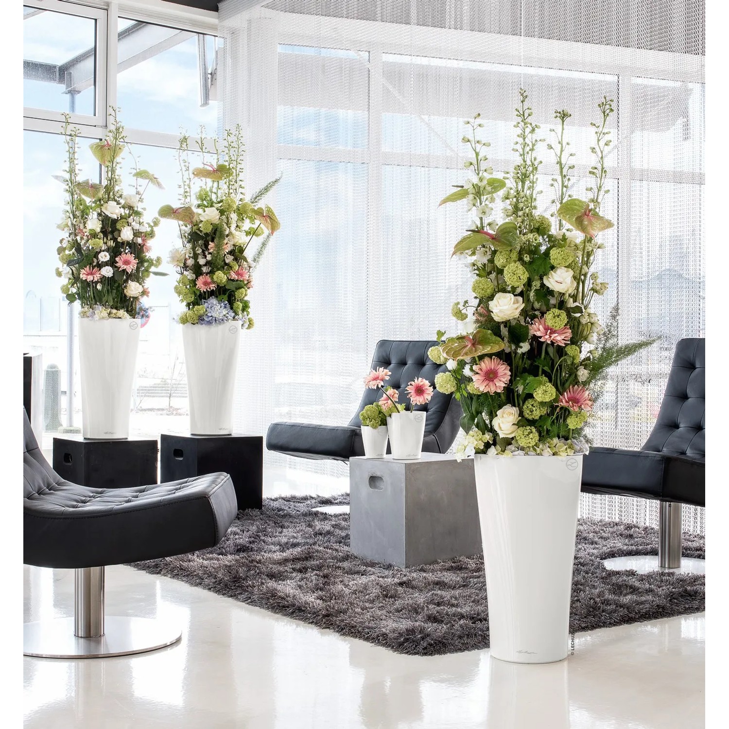Weiße Lechuza Delta Premium Pflanzsäule (40x40x75cm) mit Blumenarrangement im modernen Wohnraum.